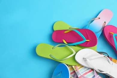 Photo of Heap of different flip flops and space for text on blue background, top view. Summer beach accessories