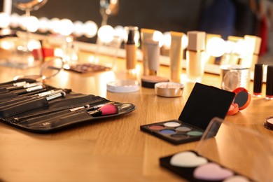 Different makeup products and brushes on wooden table indoors