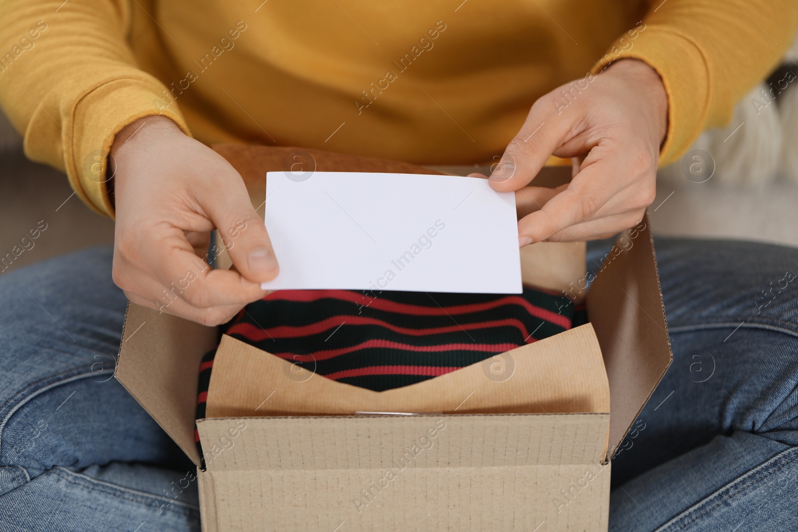 Photo of Man holding greeting card near parcel with Christmas gift, closeup