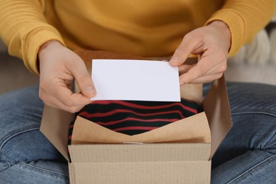 Photo of Man holding greeting card near parcel with Christmas gift, closeup