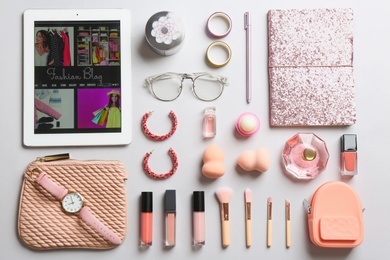 Flat lay composition with tablet, makeup products and accessories on light background. Fashion blogger