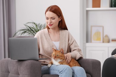 Woman with cat working in armchair at home