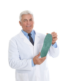 Photo of Male orthopedist showing insole on white background