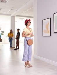 Young woman with glass of champagne at exhibition in art gallery