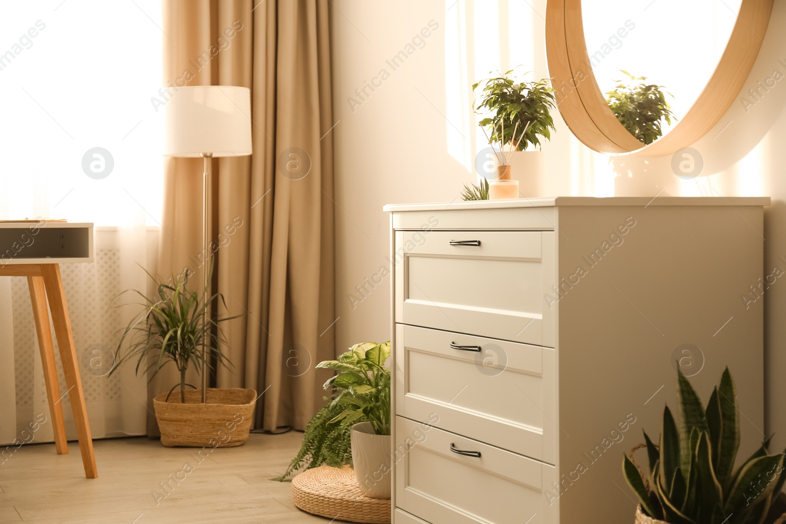 Photo of Stylish room interior with chest of drawers and round mirror