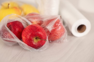 Photo of Plastic bag with fresh apples on white table, closeup