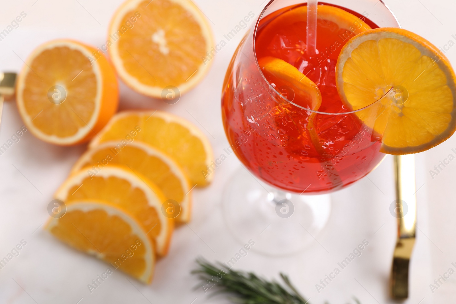 Photo of Glass of tasty Aperol spritz cocktail with orange slices on white table, above view