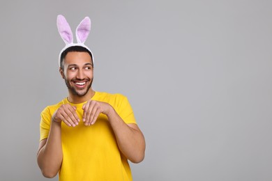 Happy African American man in bunny ears headband on gray background. Space for text
