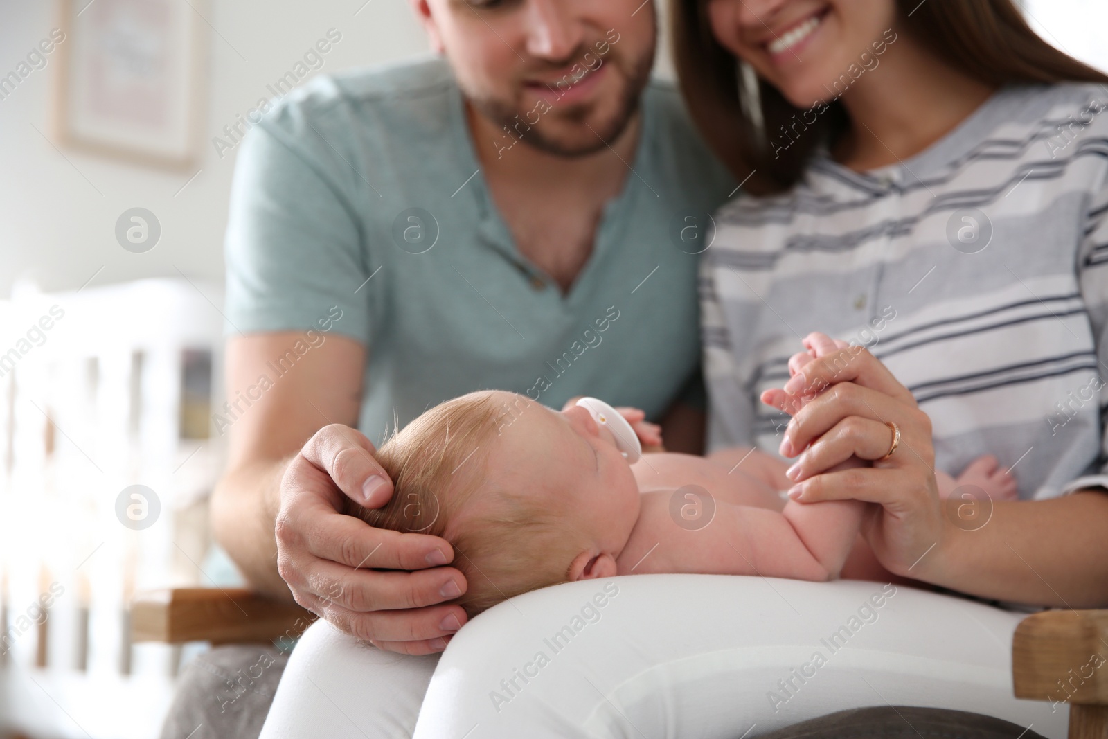 Photo of Happy couple with their newborn baby at home, closeup