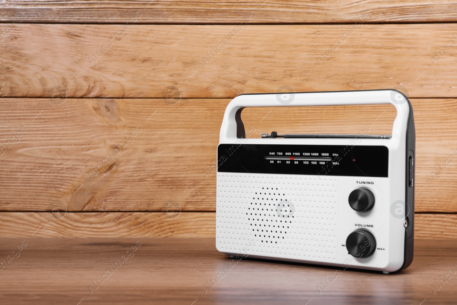 Photo of Retro radio receiver on table against wooden background. Space for text