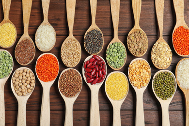 Flat lay composition with different types of legumes and cereals on wooden table. Organic grains