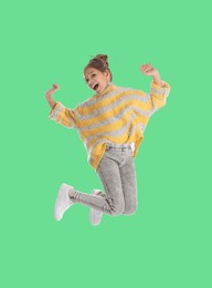 Happy cute girl jumping on green background