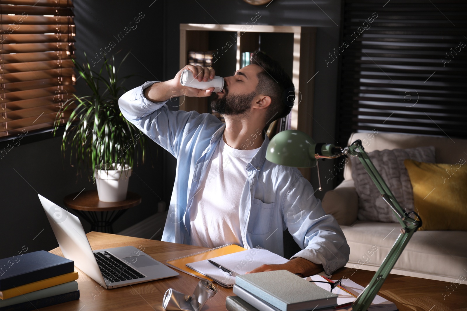 Photo of Young man with energy drink studying at home