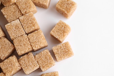 Photo of Brown sugar cubes on white background, top view. Space for text