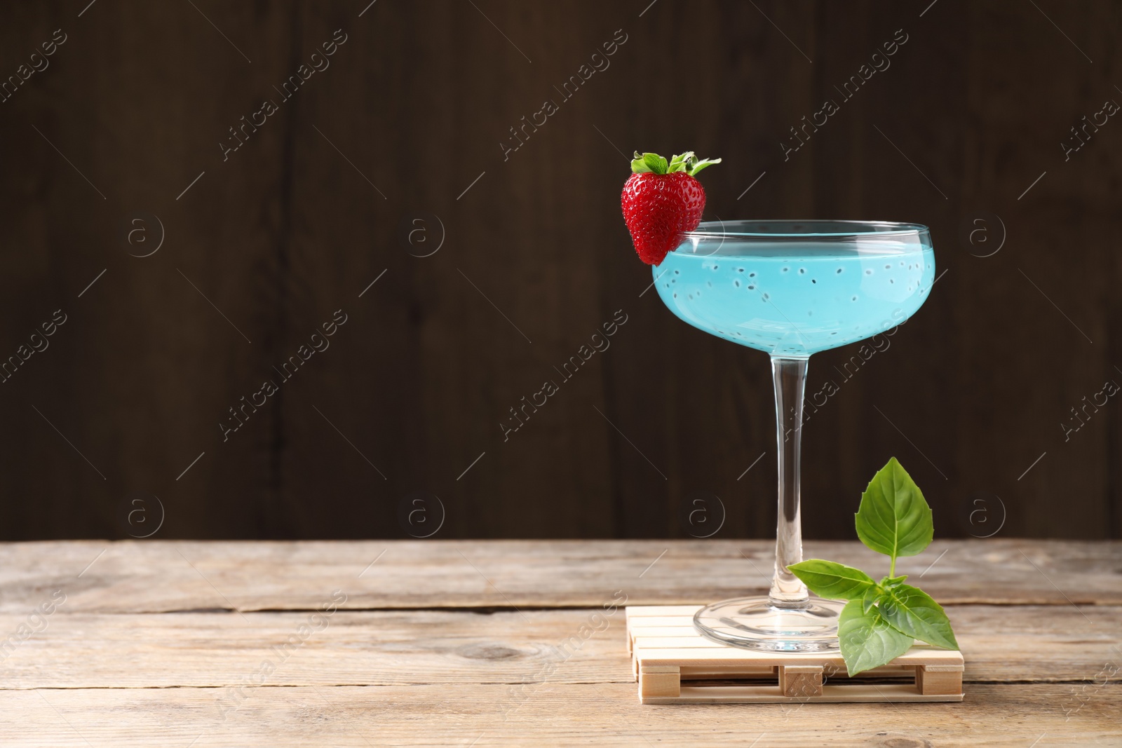 Photo of Refreshing light blue cocktail on wooden table, space for text