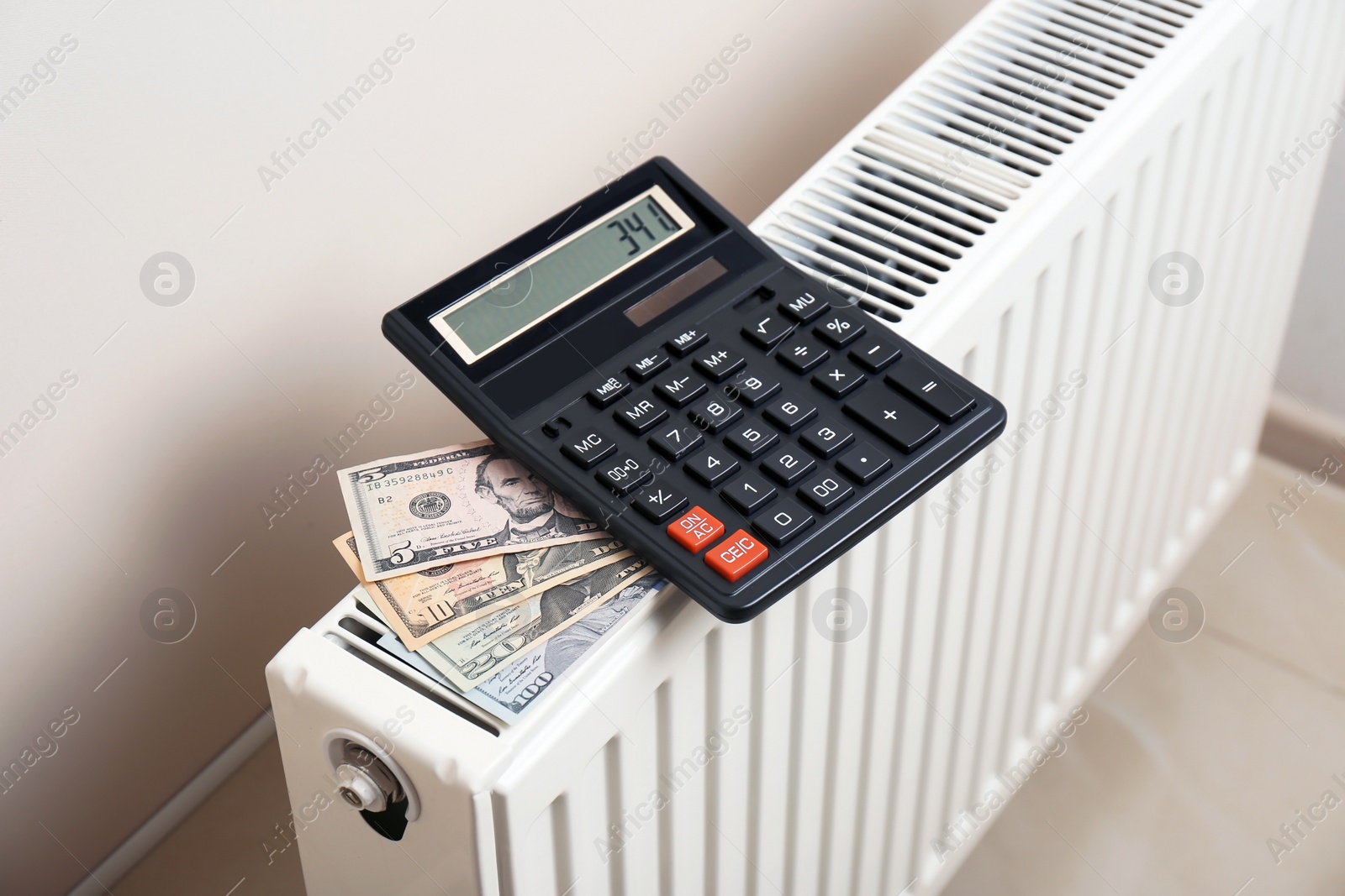 Photo of Calculator and money on heating radiator indoors
