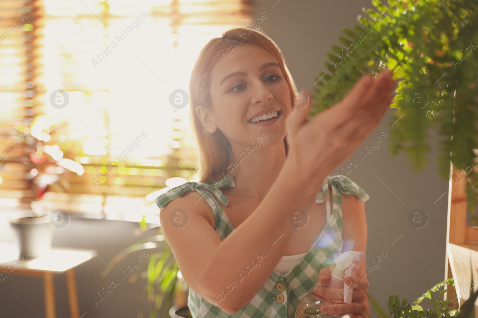 Photo of Young woman near shelves with beautiful plants at home. Engaging hobby