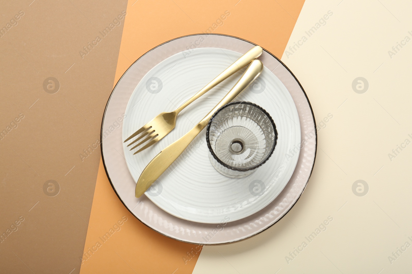 Photo of Ceramic plates, glass and cutlery on color background, top view