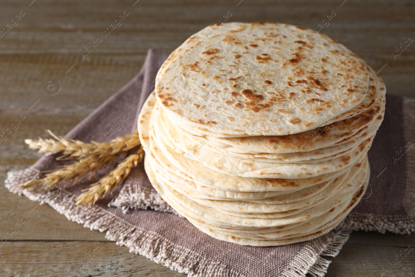 Photo of Many tasty homemade tortillas on wooden table, closeup