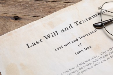 Photo of Last Will and Testament with glasses on wooden table, closeup