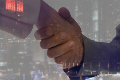 Double exposure of partners shaking hands and cityscape