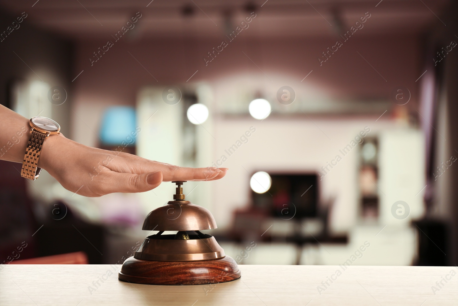Image of Woman ringing hotel service bell on blurred background, closeup