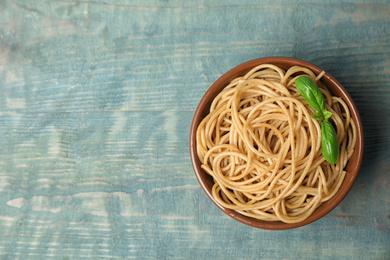 Photo of Tasty buckwheat noodles in bowl on blue wooden table, top view. Space for text