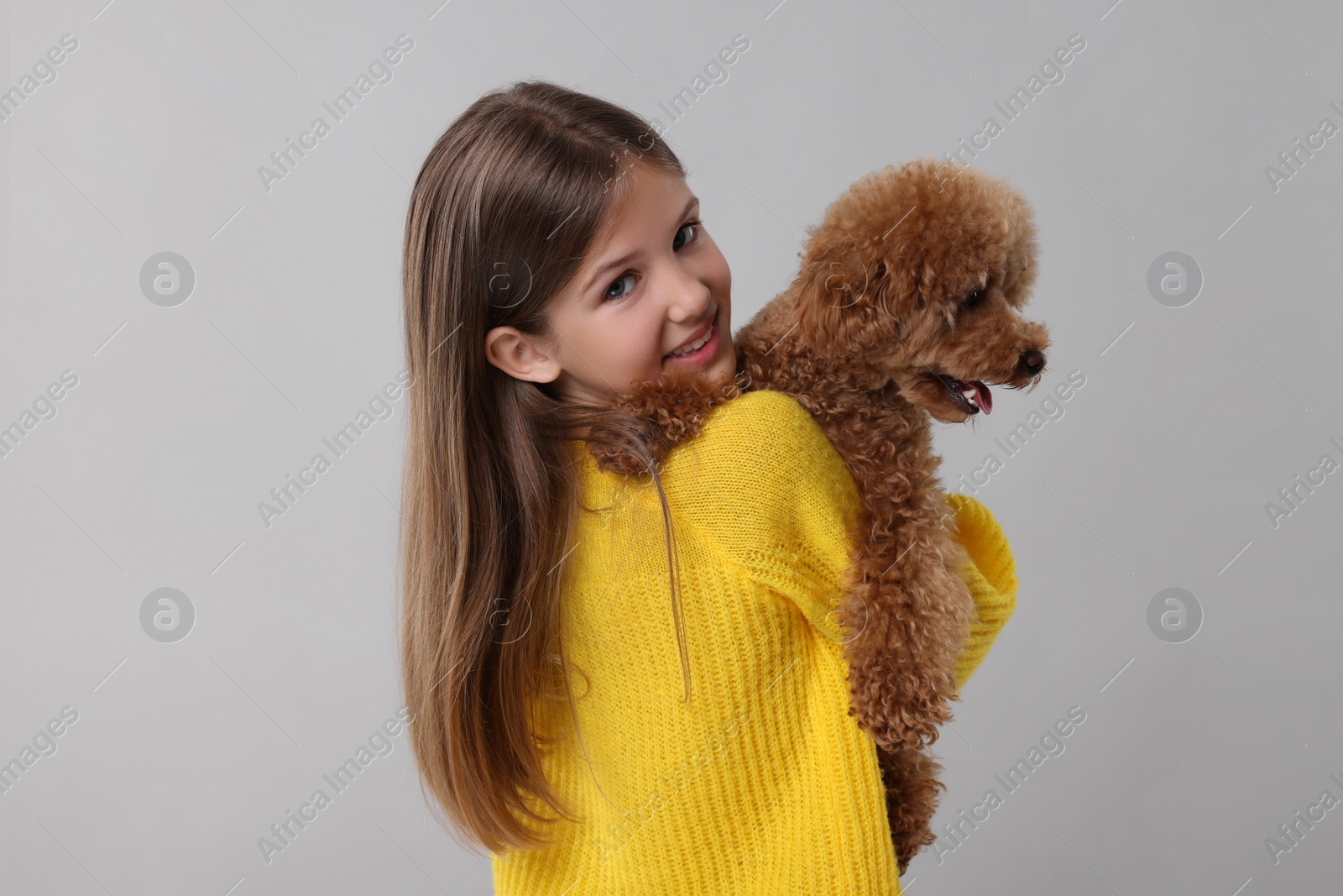 Photo of Little child with cute puppy on light grey background. Lovely pet