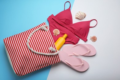 Stylish bag with beach accessories on color background, flat lay