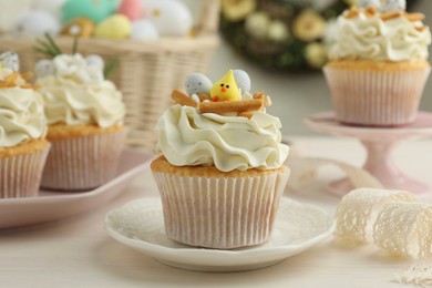 Photo of Tasty Easter cupcakes with vanilla cream on light wooden table