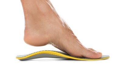 Man fitting orthopedic insole on white background, closeup. Foot care