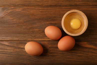 Photo of Raw chicken eggs on wooden table, flat lay. Space for text