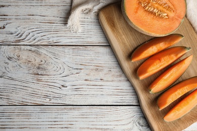 Flat lay composition with ripe cantaloupe melon on white wooden table. Space for text