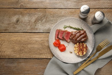 Photo of Delicious grilled beef steak served with spices and tomatoes on wooden table, top view. Space for text