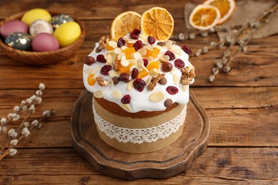 Delicious Easter cake with dried fruits, willow branches and painted eggs on wooden table