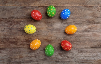 Photo of Decorated Easter eggs and space for text on wooden background, top view