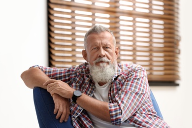 Portrait of handsome mature man sitting on chair in room