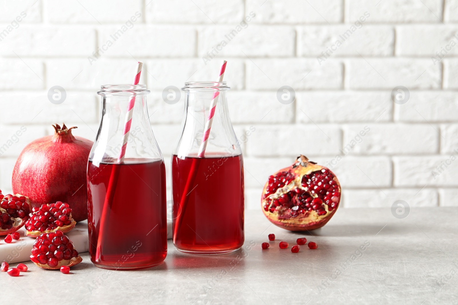 Photo of Composition with bottles of fresh pomegranate juice on table. Space for text