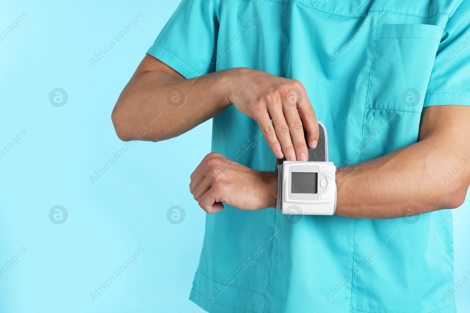Photo of Male doctor using blood pressure monitor on color background, closeup. Medical object