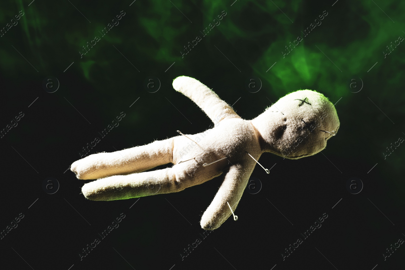 Image of Voodoo doll with pins and smoke on dark background