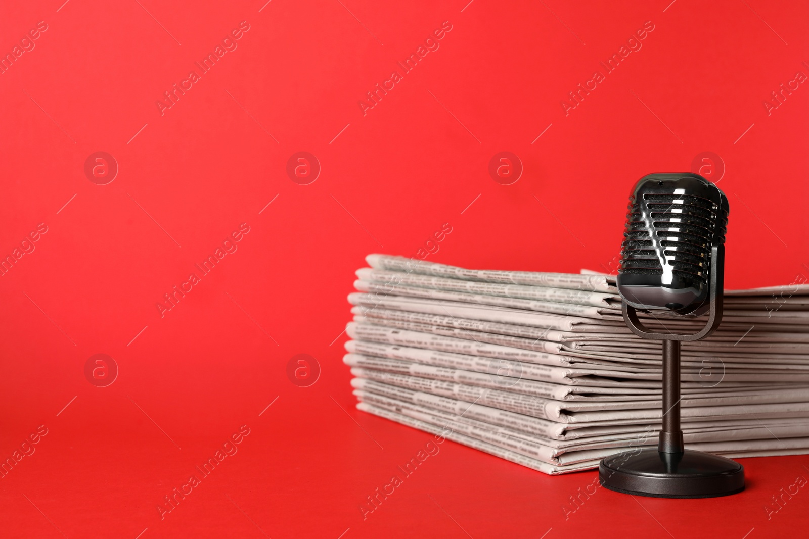 Photo of Newspapers and vintage microphone on red background, space for text. Journalist's work