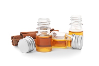 Photo of Bottles of cinnamon oil and sticks on white background