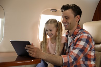 Photo of Father with daughter using tablet in airplane during flight