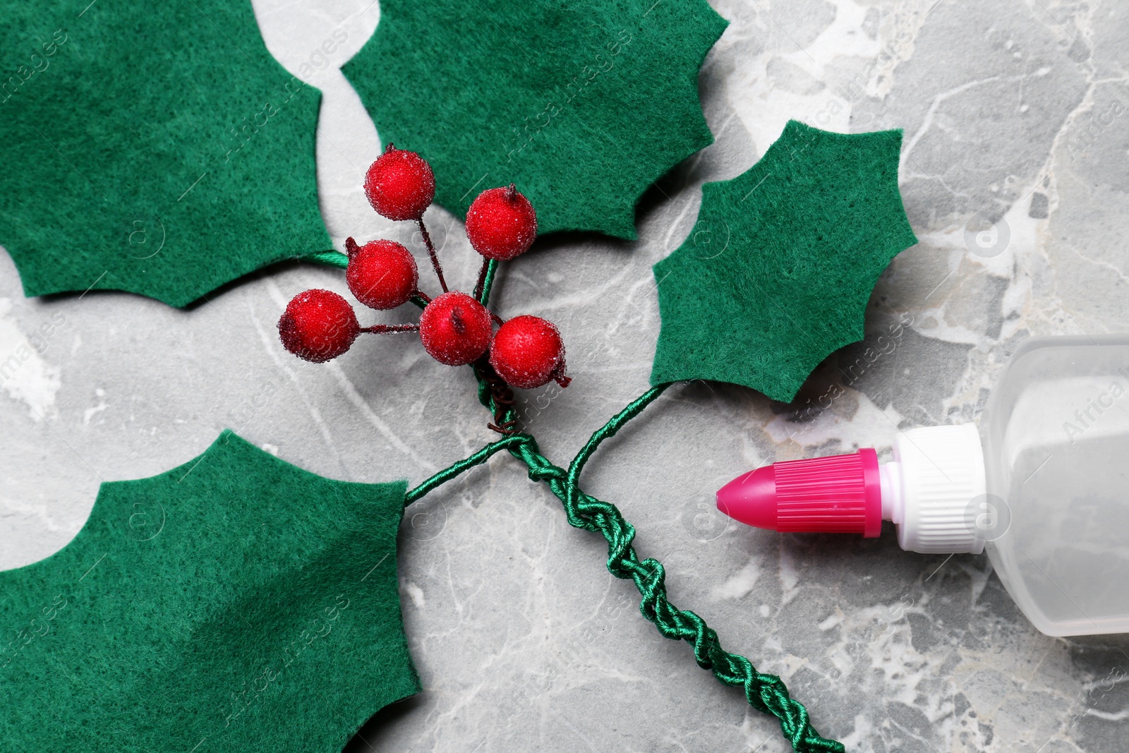 Photo of Handmade mistletoe branch branch and glue on grey table, closeup