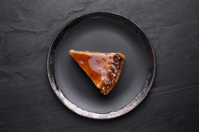 Piece of delicious cake with caramel on black table, top view