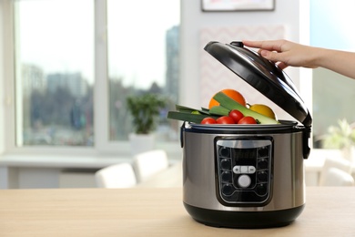 Photo of Young woman using modern multi cooker in kitchen, space for text