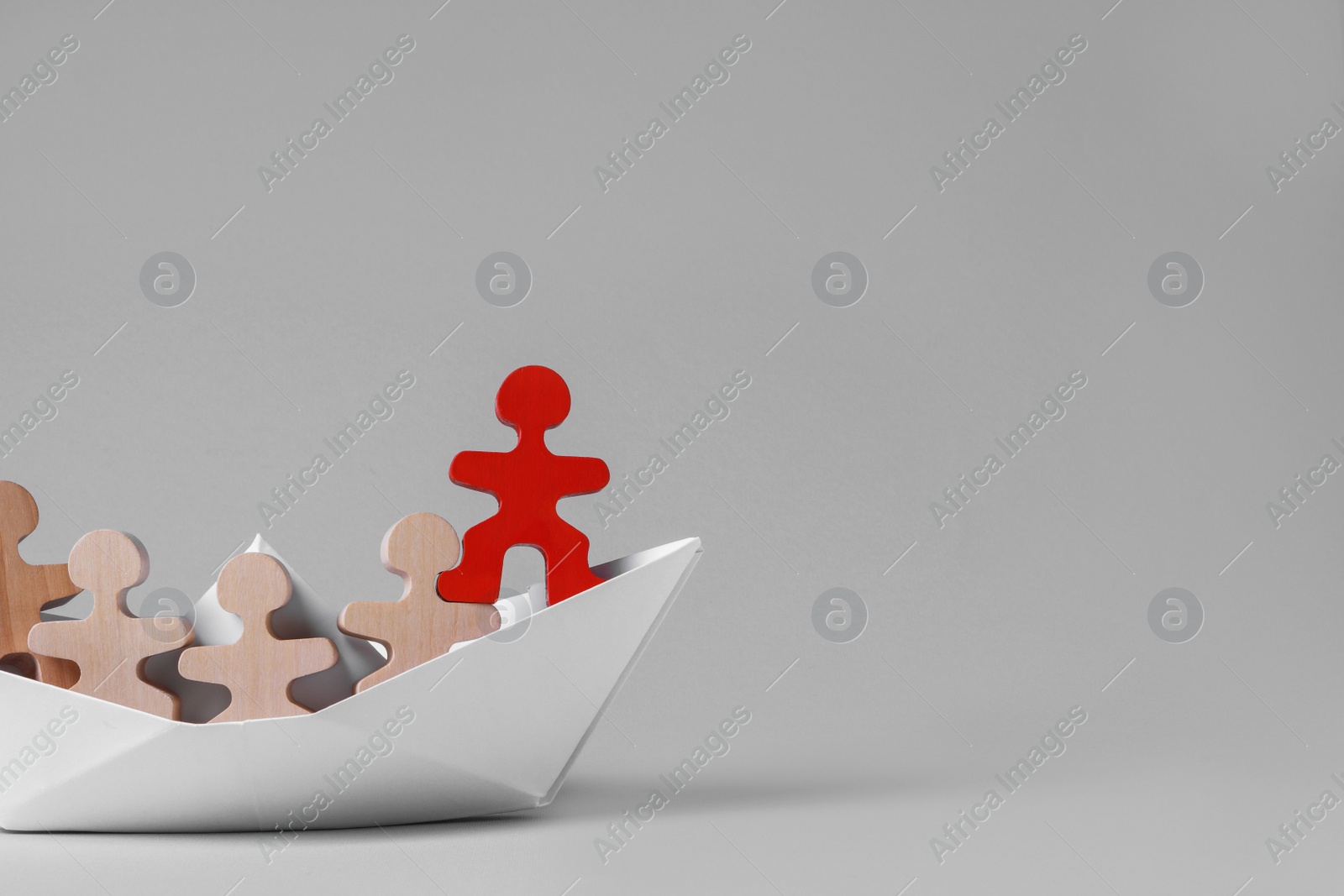 Photo of Red figure among wooden ones in paper boat on white background, space for text. Recruiter searching employee