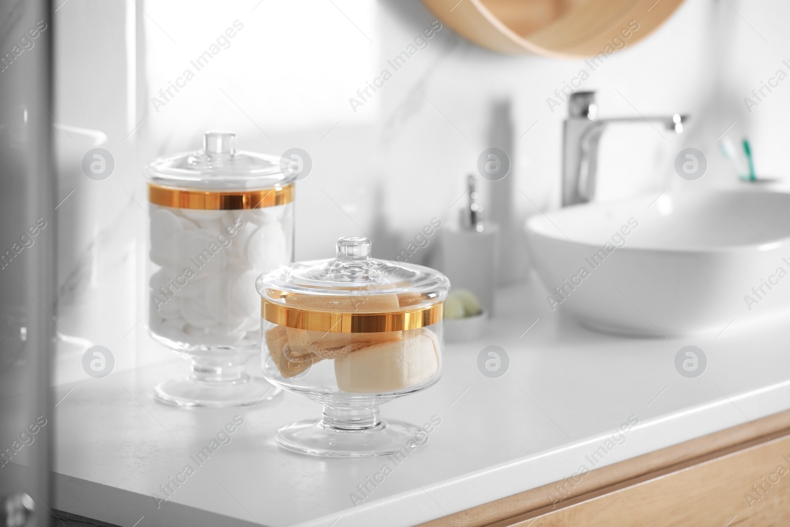 Photo of Jars with cotton pads and loofah sponges on countertop in bathroom