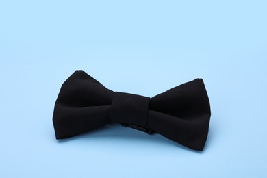 Stylish black bow tie on light blue background