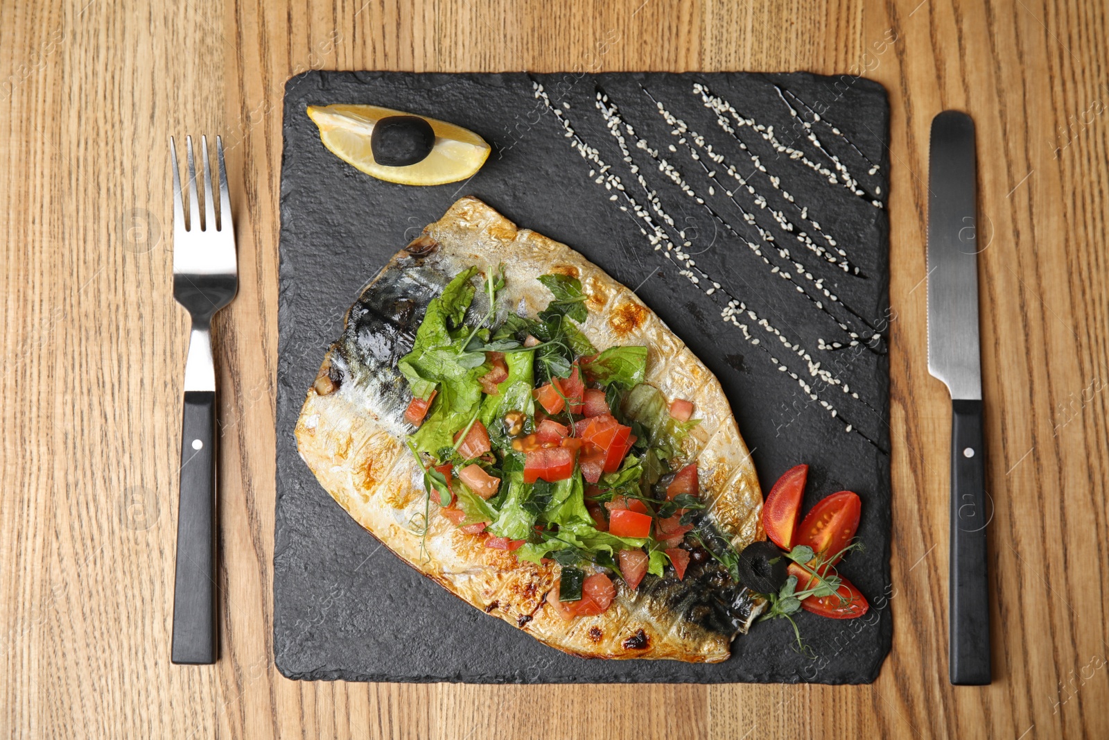 Photo of Delicious grilled fish served on wooden table, flat lay